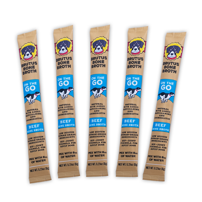 Five single-serve sticks of Brutus Bone Broth for dogs, labeled “On The Go” with beef flavor, featuring a cartoon dog image and blue accents on tan packaging. Each stick contains 0.21 oz.