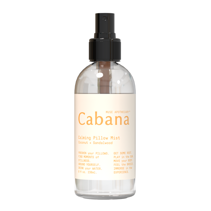 A clear spray bottle labeled Cabana Calming Pillow Mist with coconut and sandalwood, featuring a black spray top and beige label with product details and calming instructions.