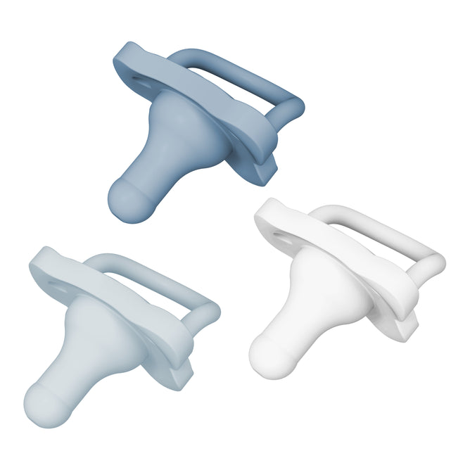 Three silicone baby pacifiers are shown against a white background. One pacifier is light blue, one is white, and one is a medium blue shade. Each has a handle and a rounded nipple.