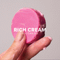A hand holds the ALINE Conditioner Bar from NOT!CE Hair Co, a round, bright pink bar with a luxurious creamy texture. Text reads: RICH CREAM YOU CAN SEE. Set against a neutral gray background, indicating it tames frizz and enhances natural shine.