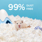 A small, light-colored hamster sits on carefresh Small Animal Bedding made from reclaimed paper fiber, White. The ultra-absorbent bedding is 99% dust-free. A blue-and-white toy and a white object are visible against a blue background.