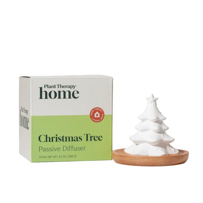 White ceramic Plant Therapy Passive Diffuser, Christmas Tree shaped, on a small wooden tray next to its product box.