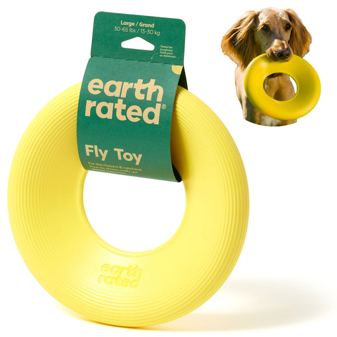 A yellow circular Flyer Dog Toy (Large) by Earth Rated features green packaging for interactive play. Ideal for dogs weighing 30-65 lbs, a playful pup eagerly grips it in its mouth.