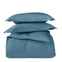 Two blue pillows rest atop the folded Classic Organic Sateen Duvet Set by Coyuchi, all displayed against a plain white background.