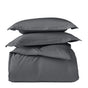 A stack of Coyuchi’s Classic Organic Sateen Duvet Set in dark gray, featuring two pillows on top and a neatly folded duvet made from organic cotton at the bottom, displayed against a plain white background.