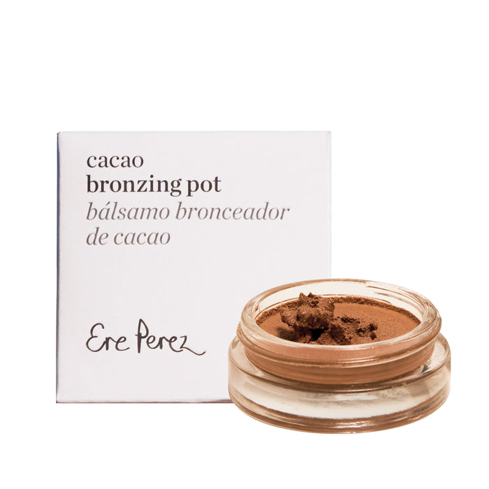A small glass jar of brown bronzing cream sits in front of a white box labeled cacao bronzing pot bálsamo bronceador de cacao and Ere Perez in script font.