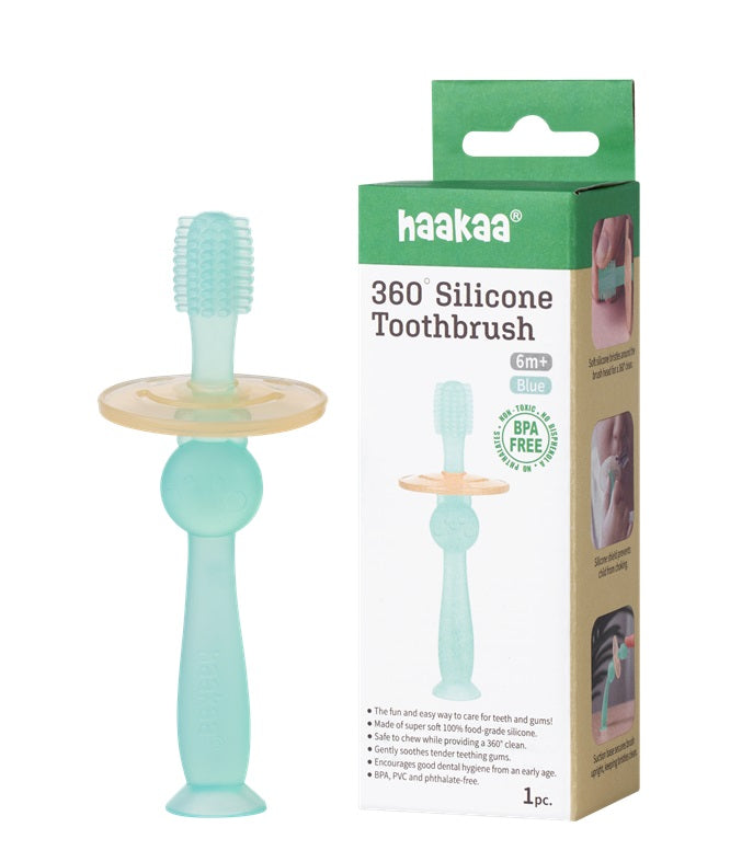 A blue 360° silicone baby toothbrush with a round safety shield is shown next to its packaging, which is labeled “haakaa 360° Silicone Toothbrush 6m+” and features product images and description.