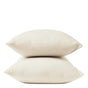 Two cream-colored pillows stacked atop one another against a plain white background, each adorned with Coyuchi Organic Crinkled Percale™ Pillowcases for a touch of breathable bedding luxury.