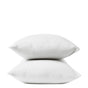 Two white pillows stacked on top of each other against a plain white background, each encased in Coyuchi’s Organic Crinkled Percale™ Pillowcases for supreme comfort.