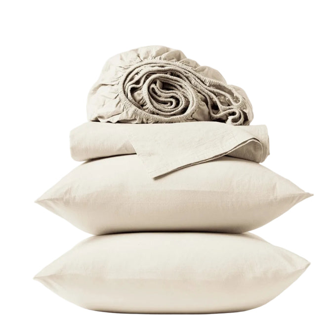 Two beige pillows are stacked atop one another, topped with a folded Coyuchi Organic Crinkled Percale™ Sheet Set and a rolled-up fitted sheet—all crafted from breathable bedding—set against a plain white background.