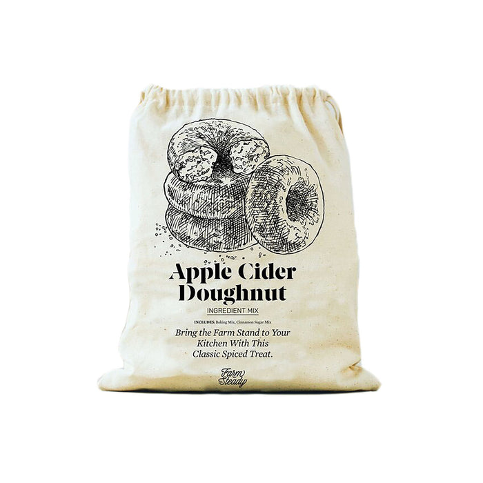 A cream-colored drawstring bag labeled Apple Cider Doughnut Ingredient Mix features a detailed sketch of three doughnuts and text describing it as a classic spiced treat.