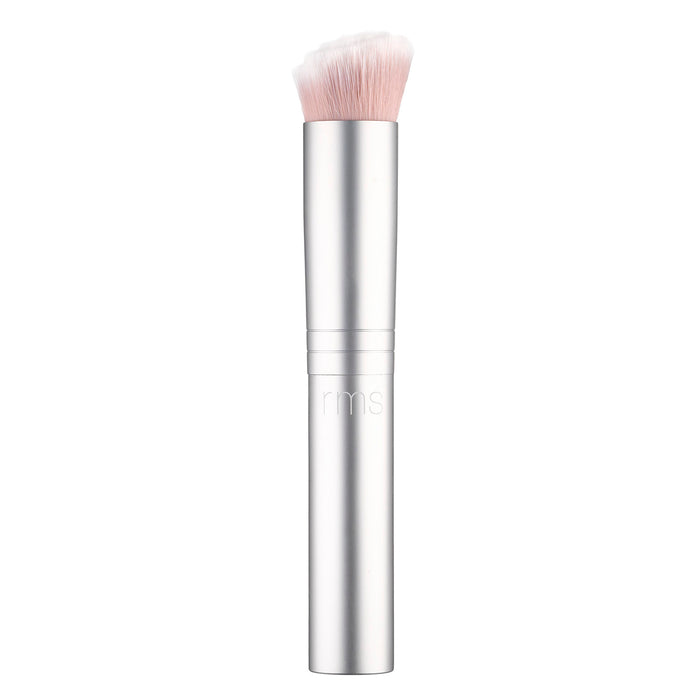 A silver makeup brush with a cylindrical handle and dense, flat-topped, light pink bristles at the top. The brush handle features the letters rms engraved near the middle.