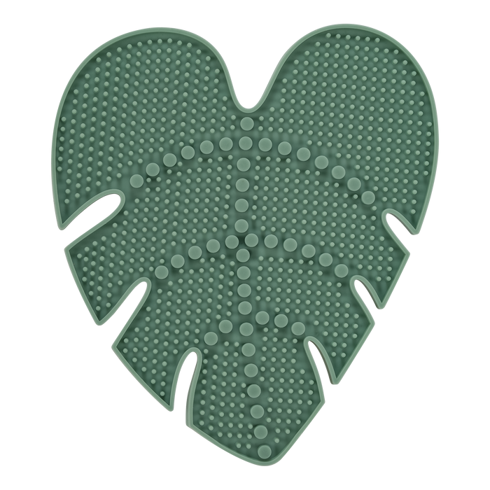 A green silicone mat shaped like a monstera leaf, with raised dots and lines covering its surface for texture.