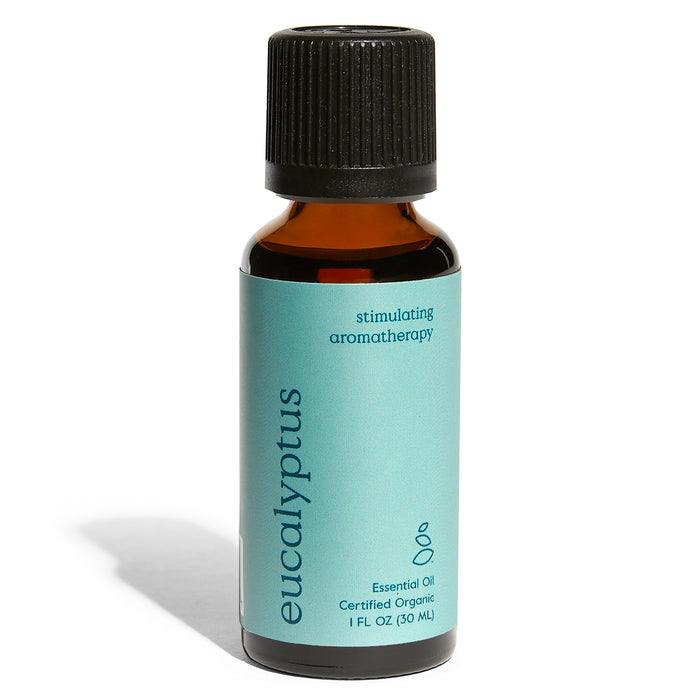 A small amber bottle with a black cap and a blue label reading eucalyptus stimulating aromatherapy essential oil, certified organic, 1 FL OZ (30 mL). The bottle casts a shadow to the left.