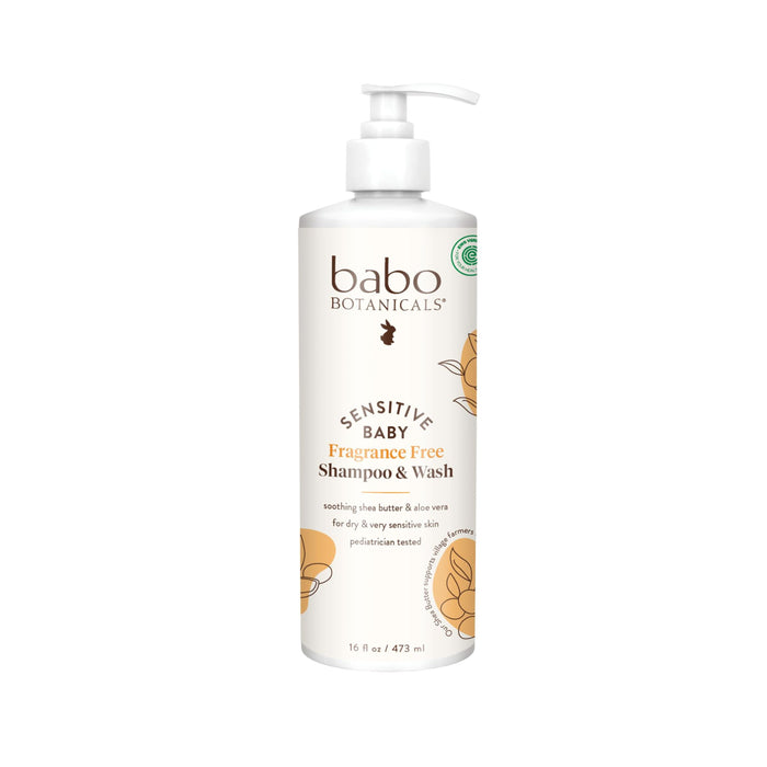 A white bottle of Babo Botanicals Sensitive Baby Fragrance Free Shampoo & Wash with a pump dispenser, featuring gold floral designs and product details in brown and gold text on the label.