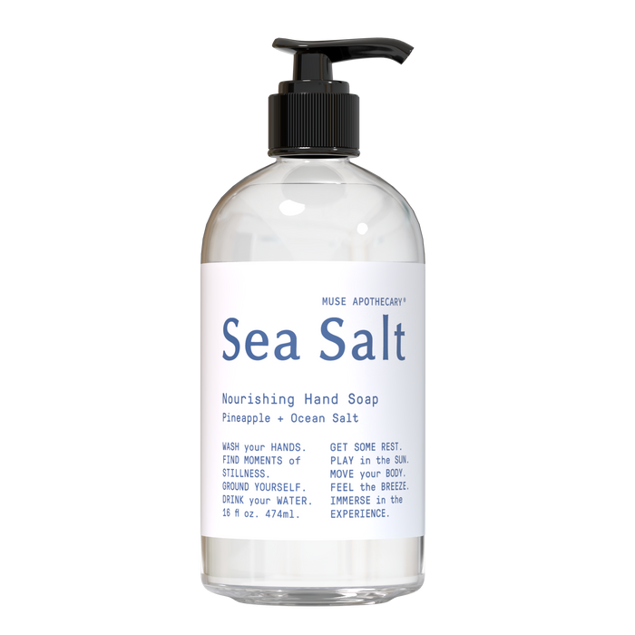A clear pump bottle labeled Sea Salt Nourishing Hand Soap by Muse Apothecary, featuring ingredients like pineapple and ocean salt, with wellness tips in blue text on a white label.