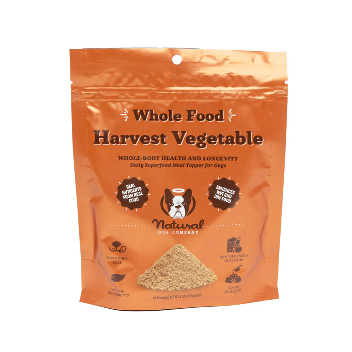 An orange resealable bag labeled Whole Food Harvest Vegetable by Natural Dog Company, containing superfood meal topper powder for dogs, with icons highlighting natural ingredients and health benefits.