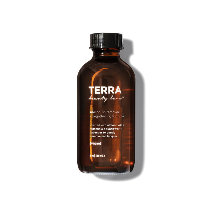 A brown glass bottle labeled TERRA beauty bar nail polish remover. The label mentions it contains almond oil, vitamin E, sunflower, and lavender, and highlights that it is vegan. The bottle is on a white background.