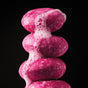 Against a black backdrop, vibrant pink, soap-covered stones are adorned with the lush foam of the ALINE Shampoo Bar by NOT!CE Hair Co, symbolizing a dedication to plastic-free hair care.