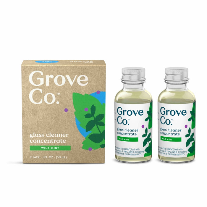A box labeled “Grove Co. glass cleaner concentrate wild mint” stands next to two small clear bottles with matching labels, green liquid inside, and mint leaf illustrations on both the box and bottles.