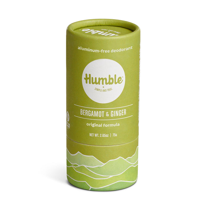 A green cylindrical container of Humble aluminum-free deodorant in bergamot & ginger scent, labeled “original formula” with minimalist mountain graphics on the bottom. Net weight is 2.65 oz (75g).
