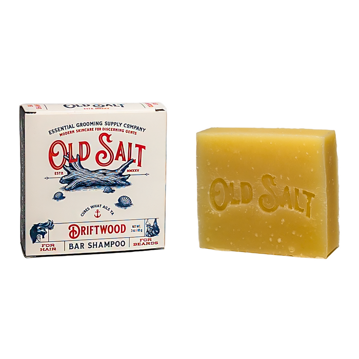 A box and bar of Old Salt Hair/Beard Shampoo. The box features a white background with blue and red nautical designs, and the tan soap bar is engraved with "OLD SALT.