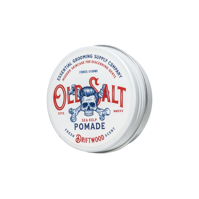 A round tin of Old Salt Pomade with sea kelp, Fresh Driftwood Scent, features a blue skull graphic and red and blue text on its white lid.