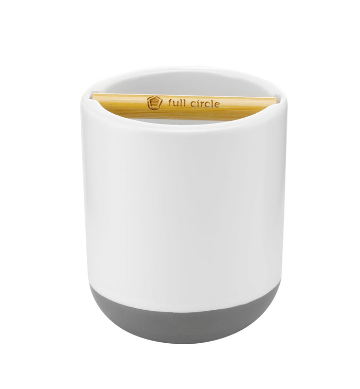 A white cylindrical container with a gray base holds a bamboo brush labeled full circle, resting horizontally across an opening at the top.