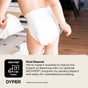A toddler in a diaper walks indoors holding another diaper, illustrating DYPERs Simply Kind Diapers and REDYPER program for centralized eco-friendly diaper and wipe disposal—making green choices easier for families.