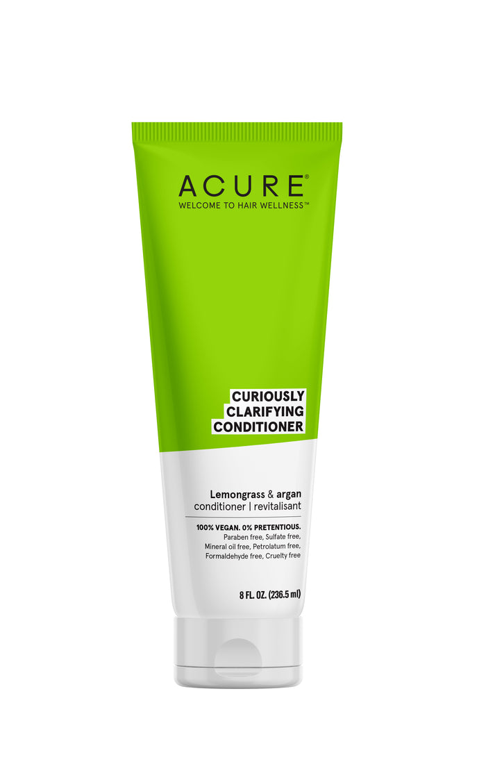A green and white tube of ACURE Curiously Clarifying Conditioner, featuring lemongrass and argan, labeled as 100% vegan and free from parabens, sulfates, mineral oil, and formaldehyde.
