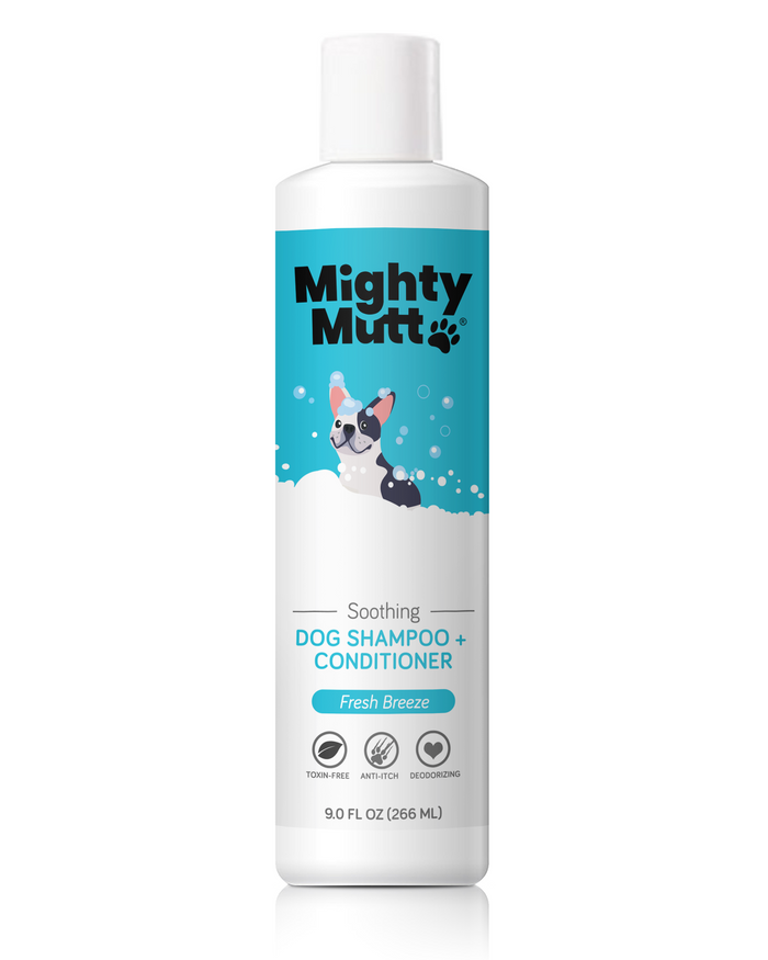 A bottle of Mighty Mutt Soothing Dog Shampoo + Conditioner with a blue label, featuring a cartoon dog in bubbles. The label highlights Fresh Breeze scent and mentions it is toxin-free, anti-itch, and deodorizing.