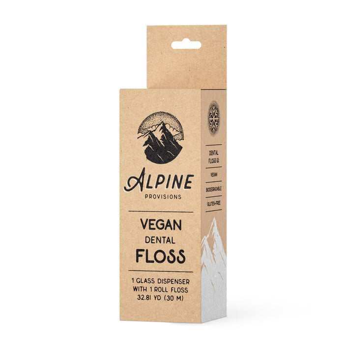 A brown rectangular box of Alpine Provisions Vegan Dental Floss with black text and a mountain logo. The packaging highlights that it is vegan, biodegradable, and comes with a glass dispenser.