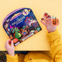 A child in a yellow sweater holds playful pumpkin and witch stickers beside a vibrant pack of eeBoo Piece & Love Halloween Stickers, displayed on a bright yellow background.