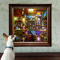 A small dog with upright ears looks at a framed Midnight Kitchen 1000 Piece Puzzle by eeBoo Piece & Love, created by artist Alfred Fernandes, hanging on a wall with floral wallpaper.