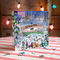 The eeBoo Piece & Love New York City Skaters 1000 Piece Puzzle features a vibrant illustration of people ice skating in Central Park, New York, with festive string lights and a wooden wall in the background.