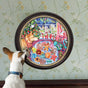 A small dog gazes at the Christmas Cookies 500 Piece Puzzle by eeBoo Piece & Love, displayed on a wall with light green patterned wallpaper. The round artwork features festive cookies, a tree, and holiday cheer.