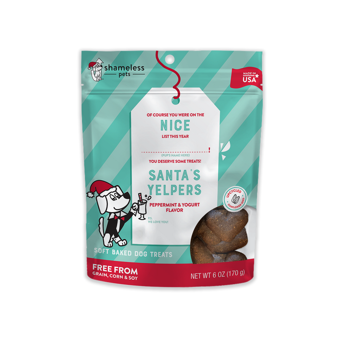 A bag of Shameless Pets Santa’s Yelpers soft baked dog treats, peppermint & yogurt flavor. The packaging is red and teal with a cartoon dog in a Santa hat and bone, labeled “Free from grain, corn & soy.”.