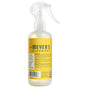A yellow spray bottle of Mrs. Meyer's Room Freshener is shown, featuring a clear trigger nozzle and detailed back label with cautions and ingredients. This versatile product is also recognized for freshening air and rooms.