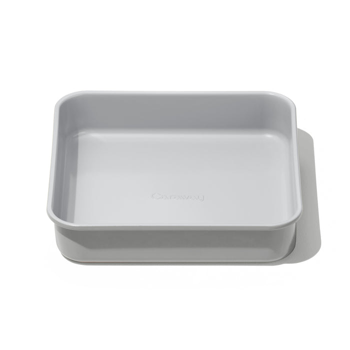 A rectangular, light gray baking pan with rounded edges and the word Caraway embossed on the bottom, photographed on a white background with a subtle shadow.