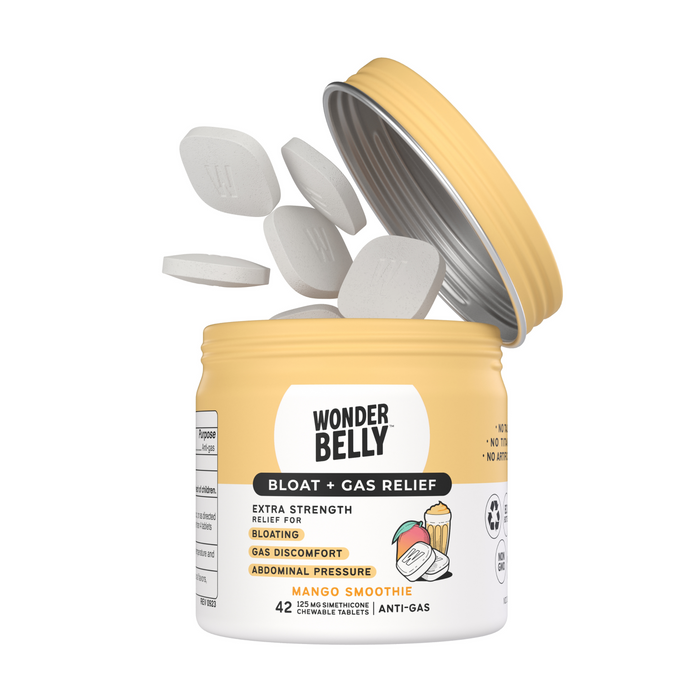 A yellow container labeled Wonder Belly Bloat + Gas Relief with chewable tablets spilling out. The label highlights relief for bloating, gas discomfort, and abdominal pressure, in mango smoothie flavor.