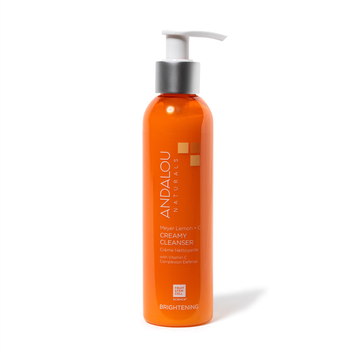 An orange bottle of Andalou Naturals Meyer Lemon + C Creamy Cleanser with a white pump dispenser, silver collar, and brightening label text on the front. The bottle stands upright against a white background.