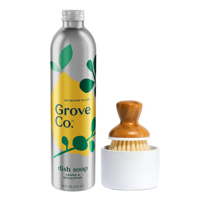 The Dish Washing Starter Set by Grove Co. includes a silver 16 fl oz bottle of Ultimate Dish Soap with lemon and eucalyptus scents, featuring a yellow and green label that promotes Go Beyond Plastic, alongside a wooden-handled dish brush in a white holder to help reduce plastic waste.