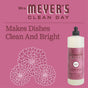 Mrs. Meyer’s Dish Soap bottle, Mum scent, on a pink background with floral designs and “Makes Dishes Clean And Bright” text, features plant-derived cleaning agents for sparkling dishes.