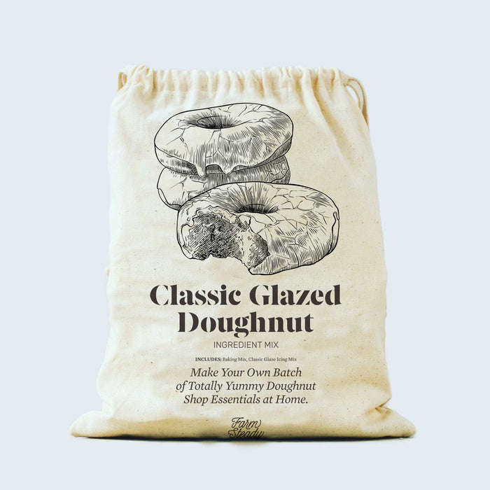 A beige drawstring bag with illustrations of glazed doughnuts and text that reads: Classic Glazed Doughnut Ingredient Mix. Make Your Own Batch of Totally Yummy Doughnut Shop Essentials at Home.
