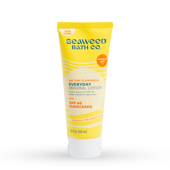 A yellow tube of Seaweed Bath Co. Everyday Mineral Lotion SPF 40 Sunscreen, featuring sea kale and prebiotics, with white and orange text and a white cap. The tube contains 3.4 fl oz (100 ml).
