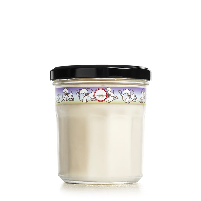 The Soy Glass Jar Candle by Mrs. Meyers, featuring a creamy white soy wax and black lid, is adorned with a decorative floral label. This cruelty-free candle adds a delightful touch to any space with its captivating design and eco-friendly vegetable soy wax.