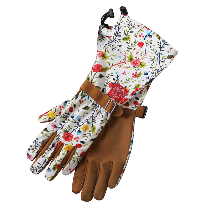 A pair of gardening gloves with brown suede palms and floral-patterned fabric on the cuffs and back, featuring adjustable straps and a colorful design with flowers and leaves.