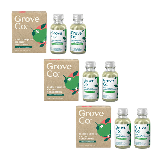 The image shows Grove Co.s Multi-Purpose Cleaner Concentrates, 3-pack. Featuring a natural motif with green leaves and a red flower, the transparent bottles have white caps and come in brown boxes. The plant-based formula emphasizes the clean design and eco-friendly fragrances.