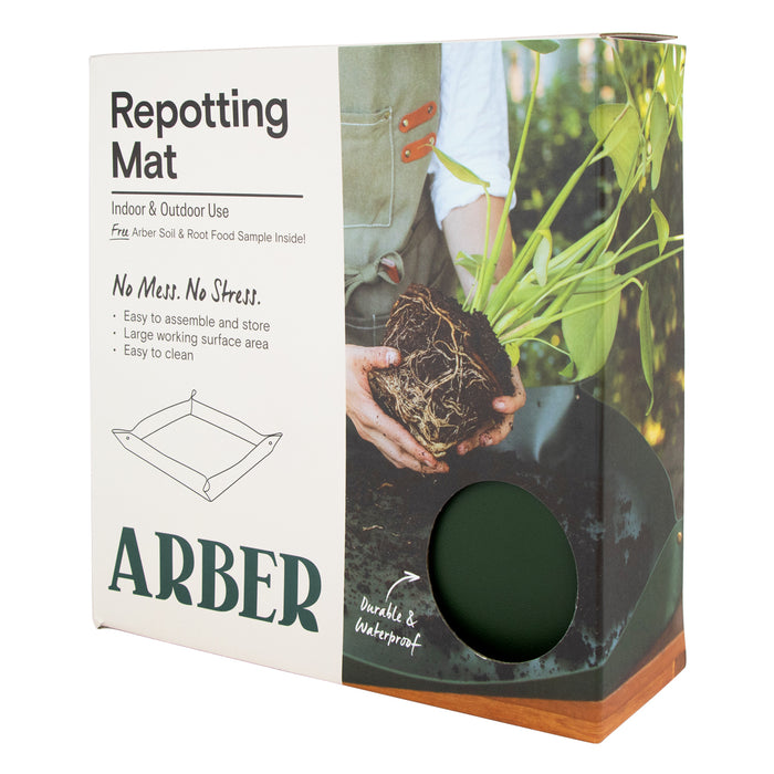 A box labeled Repotting Mat by Arber shows a person holding a plant with exposed roots. The packaging highlights indoor/outdoor use, easy cleaning, and a durable, waterproof mat visible through a circular window.