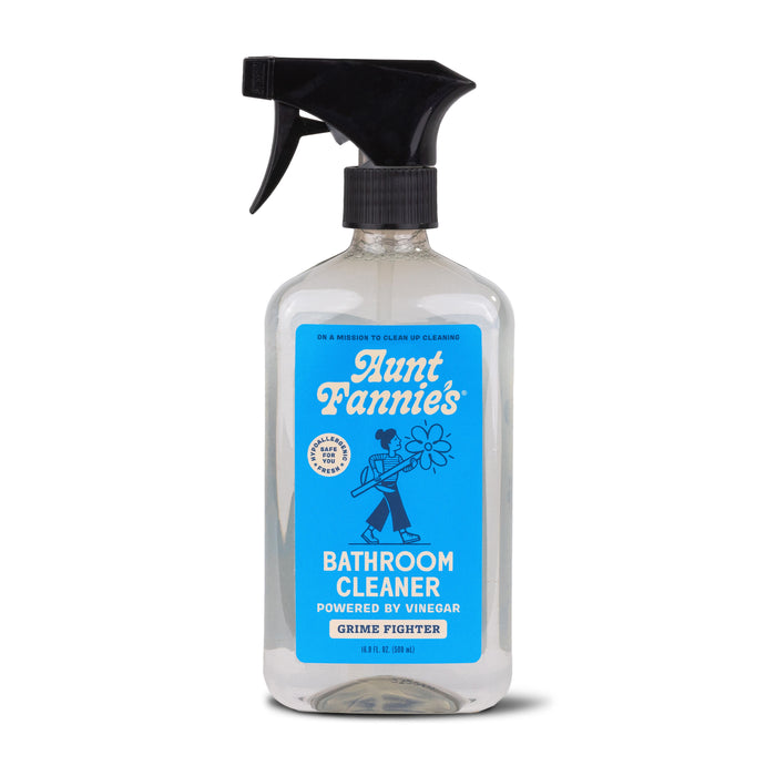 A clear spray bottle of Aunt Fannie’s Bathroom Cleaner with a black trigger nozzle and a blue label featuring a cartoon figure and text that reads Powered by Vinegar, Grime Fighter, 16.9 fl oz.